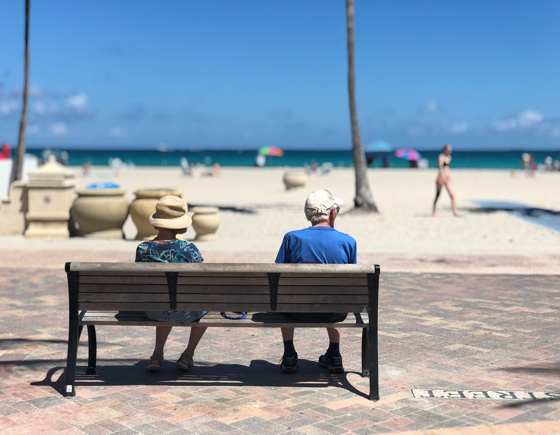 older couple sitting on a bench at the beach