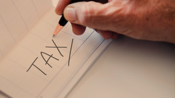 person writing "tax" on piece of paper