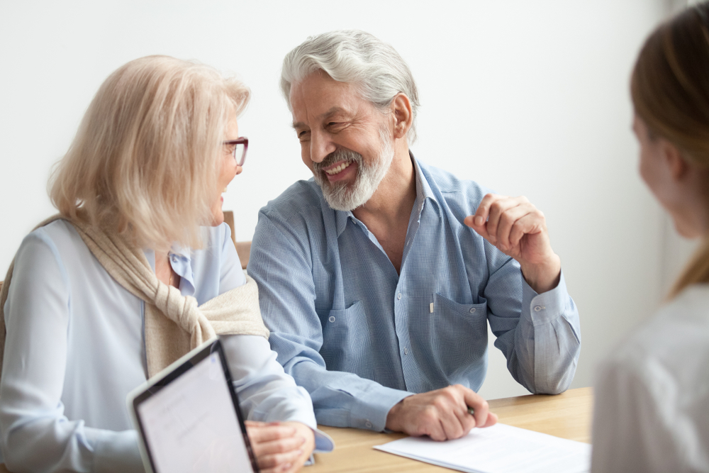 Happy senior family talking smiling at meeting with financial advisor, older clients ready to buy medical health life insurance
