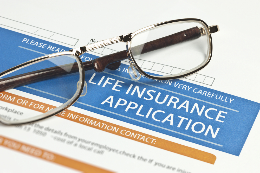 life insurance application for IUL with pair of glasses laying over the application