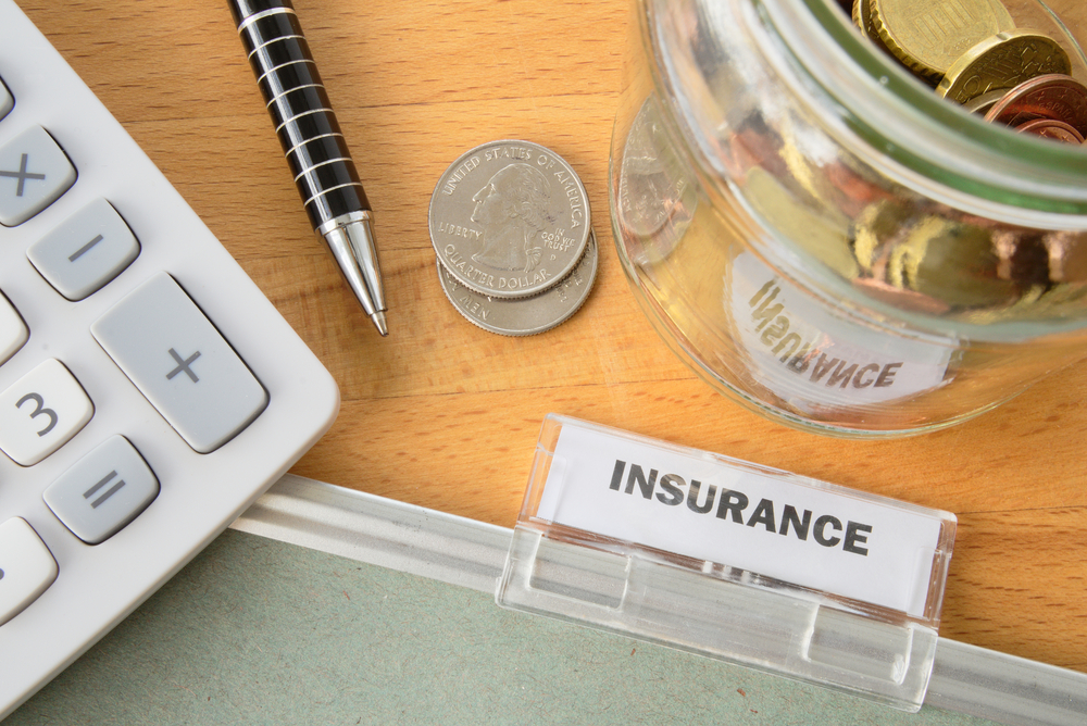 life insurance folder with calculator, pen, and change beside it