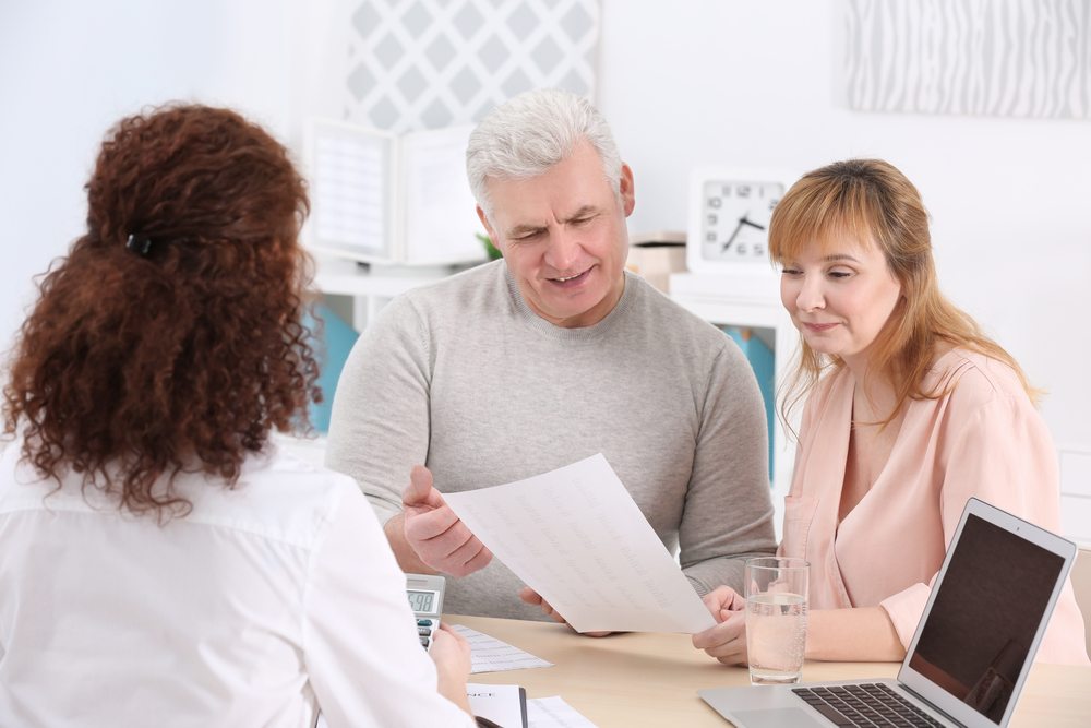 middle-aged couple speaking to their financial advisor about life insurance policies